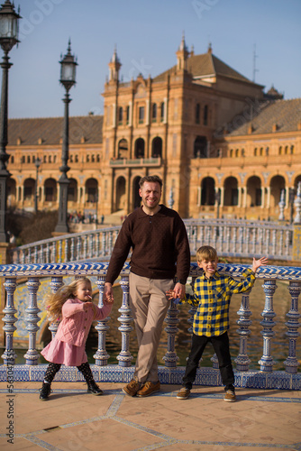SEVILLE, SPAIN father and kids play outside Plaza Espana  in Seville, Spain. It is a landmark example of the Renaissance Revival style in Spanish architecture..Important information photo