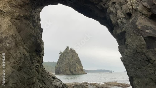 Famous natural rock arch 'Hole-in-the-Wall in Olympic National Park, with a view of the Pacific Ocean and sea stack in the distance - Rialto Beach, Washington, USA photo