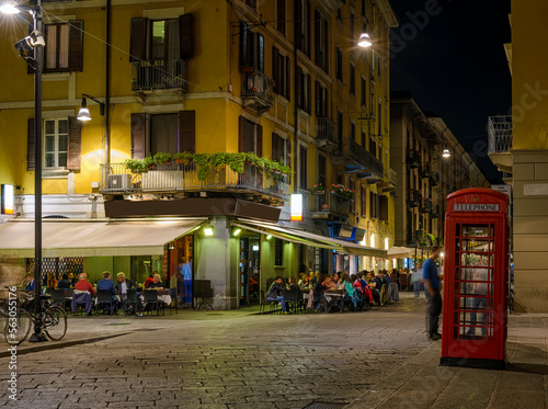 Old street with restaurant tables Milan, Italy. Night cityscape of Milan. Architecture and landmarks of Milan.