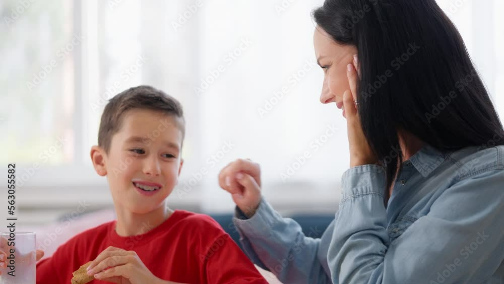 Young mother watching little son drink milk and eat cookies, healthy nutrition Young mother watching little son drink milk and eat cookies, healthy nutrition