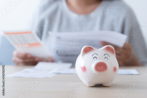 Woman save money for household expenses in piggy bank.