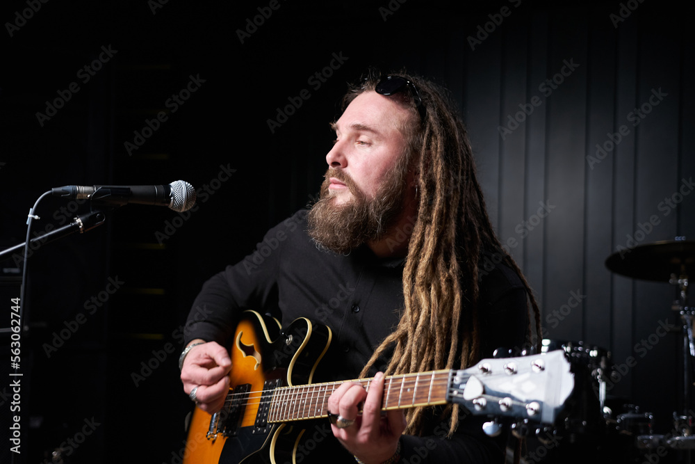 Obraz premium Guitarist man plays an electric guitar Close-up at studio
