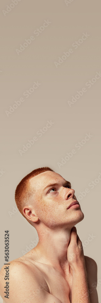 Naklejka premium Handsome young red-haired man posing isolated over grey studio background. Male natural beauty. Concept of men's health, posing, beauty, body and skin care.