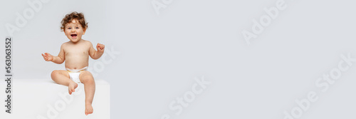 Smiling happy child, toddler boy, baby in diaper joyfully sitting and laughing on white background. Concept of childhood, motherhood, life, birth. Banner