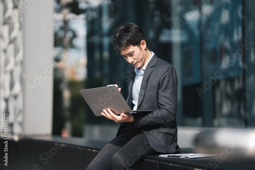 Handsome young manager working on laptop while sitting outdoors on the stairs, concept of work life balance.
