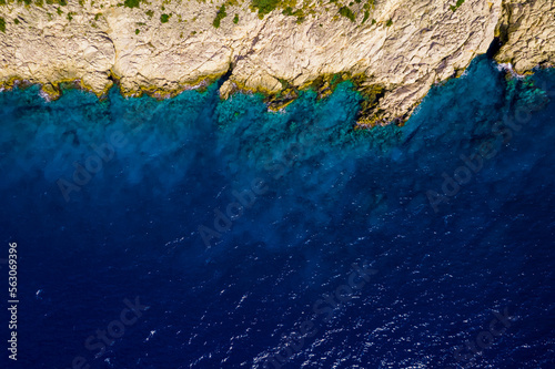 Bird's-eye view of a white yacht and a yellow lifeboat in the azure sea. Drone shot top view on the Mediterranean