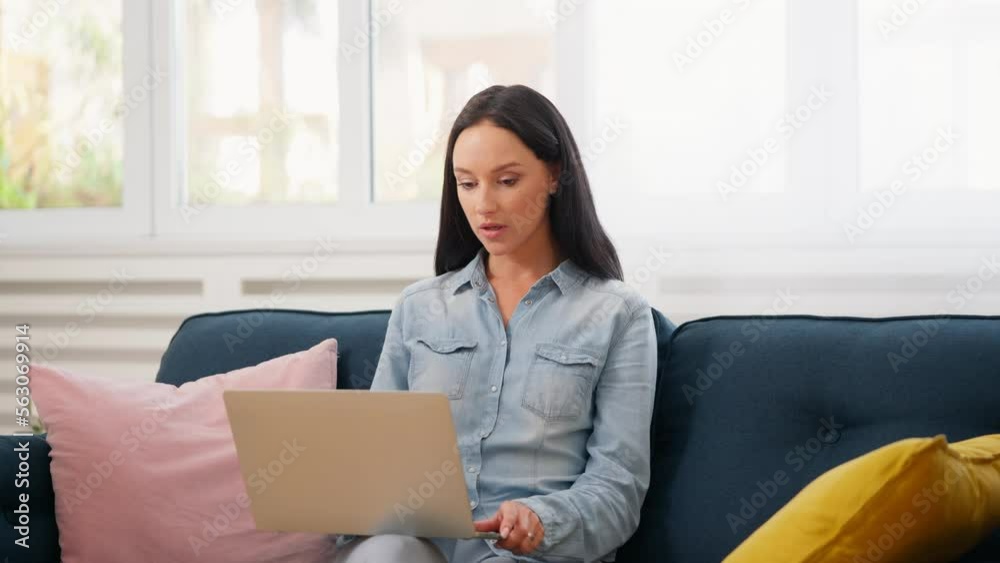 Woman having work call on laptop with her son running around in a superhero cape Woman having work call on laptop with her son running around in a superhero cape