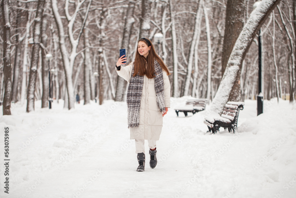 Young beautiful woman in a gray down jacket in a winter snowy park Young beautiful woman in a gray down jacket in a winter snowy park