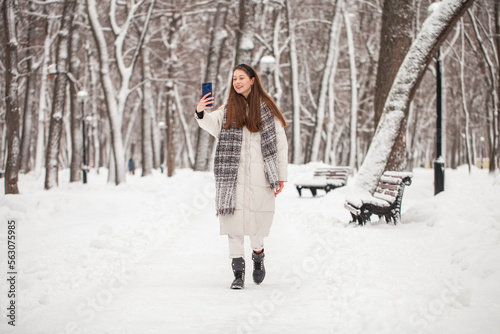 Young beautiful woman in a gray down jacket in a winter snowy park
