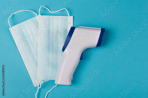 Top view of pyrometer near medical masks on blue background. photo