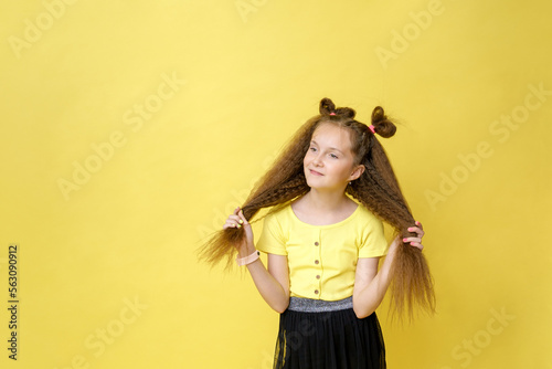 Cool cute girl with a trendy hairstyle in a yellow top on a yellow background with bright emotions