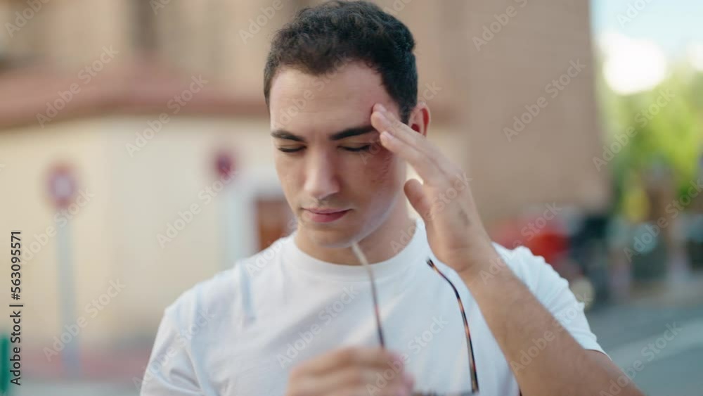 Young hispanic man stressed suffering for headache at street Young hispanic man stressed suffering for headache at street