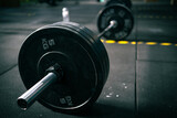 View from the side of a barbell with heavy weights ready to be lifted by a person in a fitness gym.
