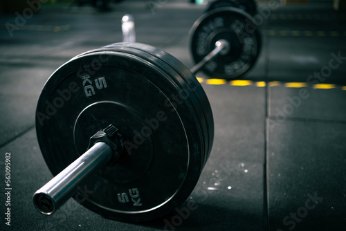 View from the side of a barbell with heavy weights ready to be lifted by a person in a fitness gym.