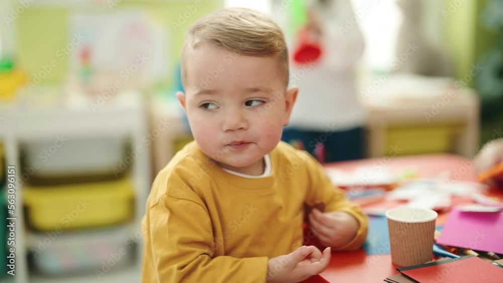 Adorable blond toddler standing with relaxed expression at kindergarten Adorable blond toddler standing with relaxed expression at kindergarten