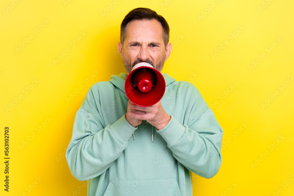 Photo of angry dissatisfied boss wear khaki hoodie hold microphone scream loud bad finance results company isolated on yellow color background Photo of angry dissatisfied boss wear khaki hoodie hold microphone scream loud bad finance results company isolated on yellow color background