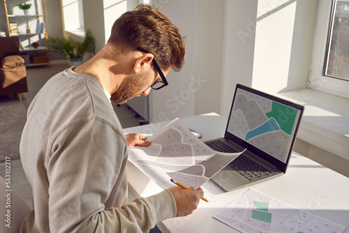 Konstfotografi Side view portrait of a professional cartographer working with printed cadastral map at table on his workplace