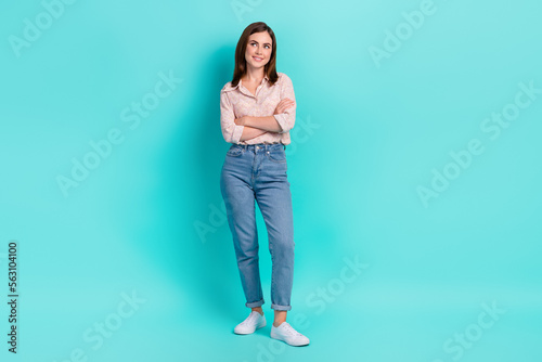 Full length photo of funny dreamy lady wear pink shirt looking empty space arms folded isolated turquoise color background