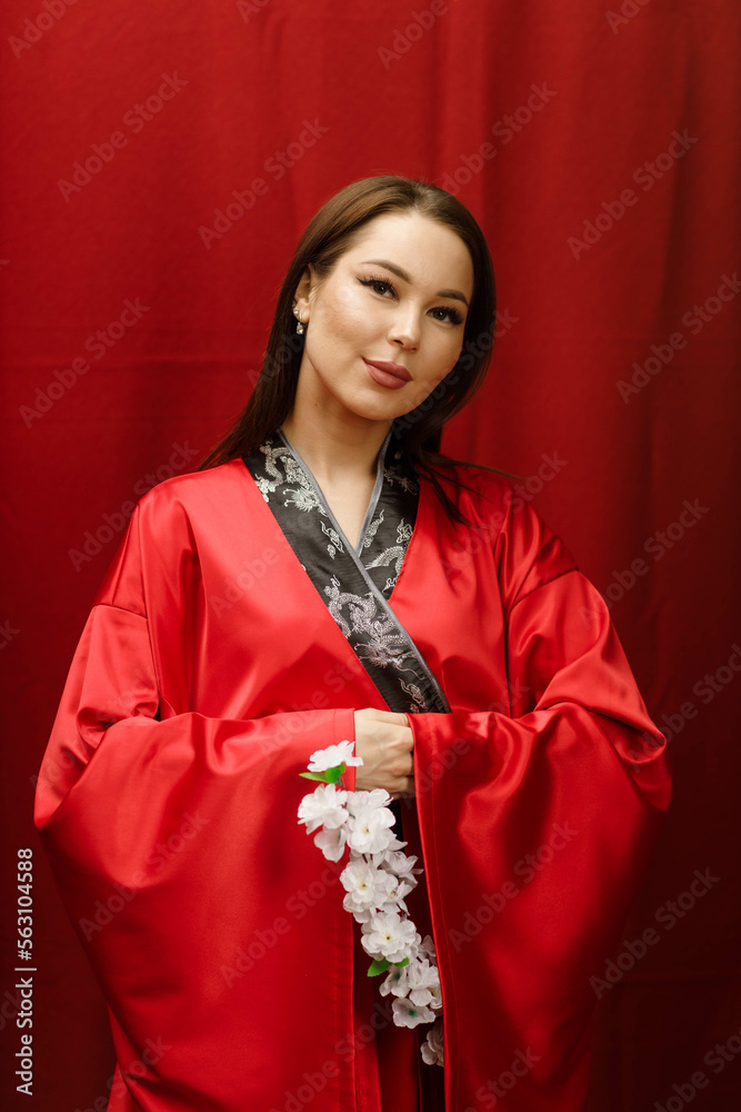 a girl in a red kimono with a branch of white sakura on a red background