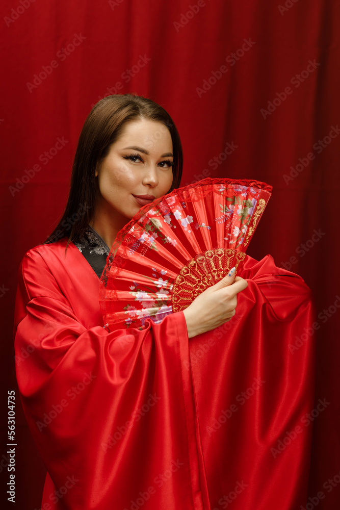 Obraz premium a girl in a red kimono with a red fan on a red background