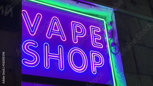 vape shop electronic cigarette neon colored window showcase sign lights glow up attracting customers on the street at night.concept vape shop.