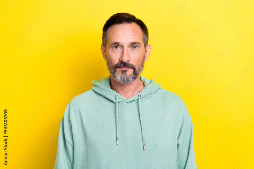 Closeup portrait of serious mature age man wear sportive hoodie brunet hair grey beard entrepreneur isolated on bright yellow color background Closeup portrait of serious mature age man wear sportive hoodie brunet hair grey beard entrepreneur isolated on bright yellow color background