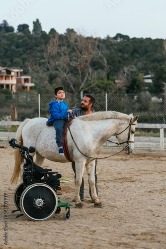 Wheelchair and disabled boy on horse in a physiotherapy session