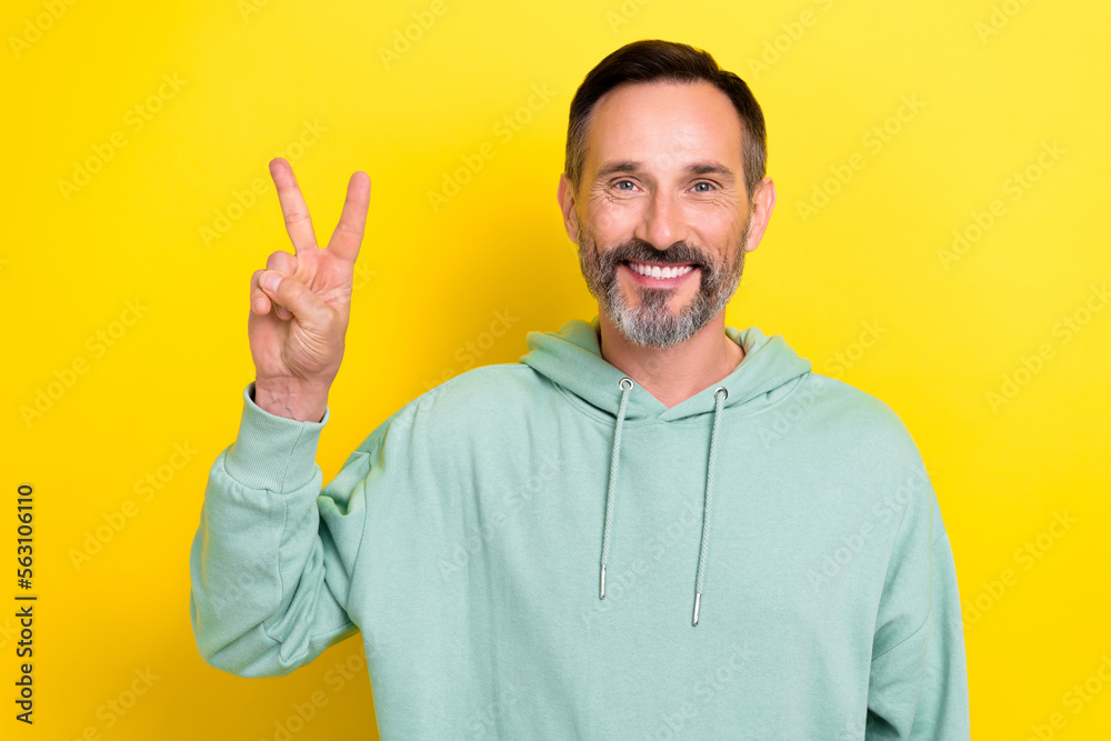 Photo of friendly good mood person middle age man grey beard showing v-sign hello world peace for everyone isolated on yellow color background Photo of friendly good mood person middle age man grey beard showing v-sign hello world peace for everyone isolated on yellow color background