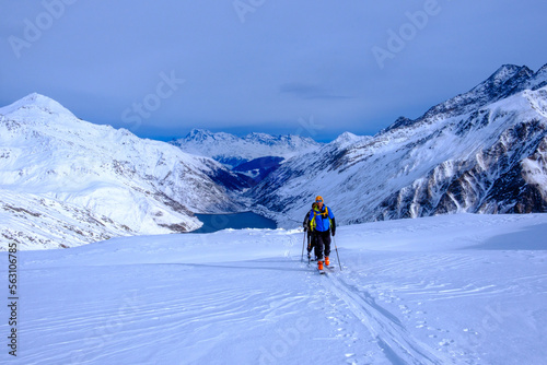 Due sci alpinisti sulle Alpi Lepontine, Pizzo dell'Uomo, Massiccio del San Gottardo, Svizzera. Sullo sfondo il lago del Passo Lucomagno