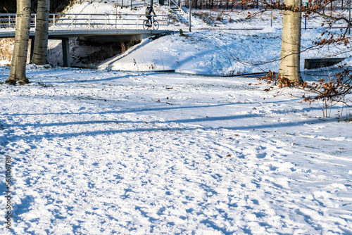 Winter in Almere, the Netherlands. Footprints on a snowy path in a city park. The cyclist rides in the snow. 