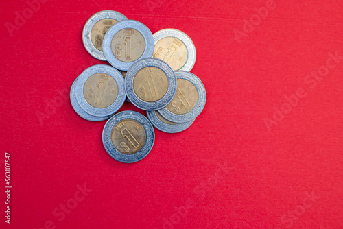 Monton de monedas de un peso en un fondo rojo economia mexicana 