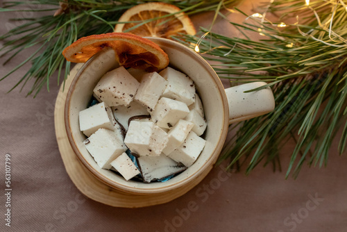 Marshmallows in a cup, dried orange and Christmas tree branches near the cup