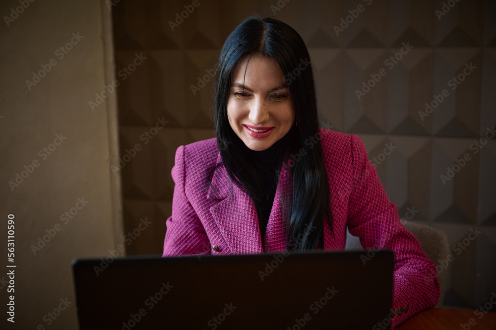 Smiling confident woman entrepreneur 40-45 years old, dressed in a stylish crimson jacket, talking to business clients via video link. Successful entrepreneur at online meeting with business partners Smiling confident woman entrepreneur 40-45 years old, dressed in a stylish crimson jacket, talking to business clients via video link. Successful entrepreneur at online meeting with business partners