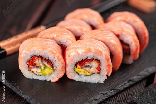 Sushi roll maguro with tuna, smoked eel, avocado and tobiko on black board close-up. Sushi menu. Japanese food.