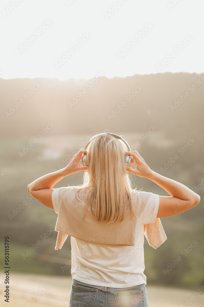 Happy millennial woman with eyes closed listening music outdoors