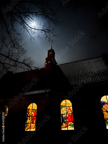 Stained glass window in the church of St. Francis of Assisi in Miotek, Silesia, Poland seen from the outside in the evening. Saint Francis in the foreground photo