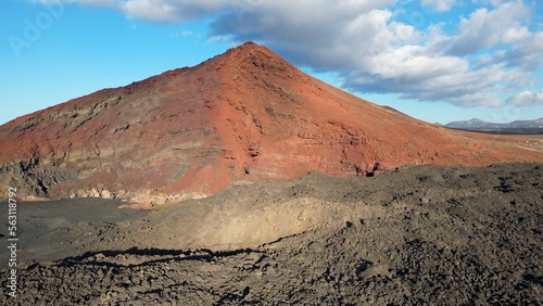 Drone aerial view of red Volcano Bermeja and volcanic black lava soil in Canary Islands, nearby Charco verde El Golfo - tourist attraction in Tymanfaya biosfere reserve Lanzarote