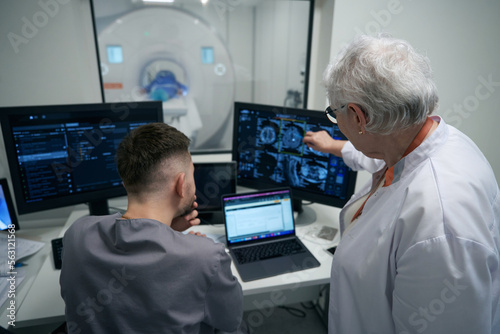 Woman doctor and her colleague are analyzing results of CT photo