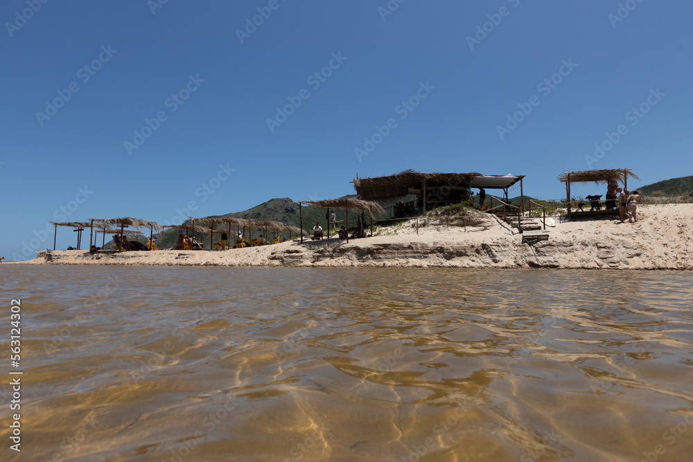 Quiosque na areia em praia turística isolada com rio desaguando no mar