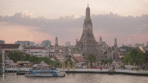 Wat Arun Ratchawararam Ratchawaramahawihan Buddhist Temple and Chao Phraya River in Sunset Crowd of Tourists Bangkok, Thailand photo