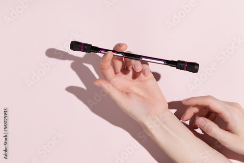 Woman hold pen spinning in your hand on pink background. Hand motor skills.