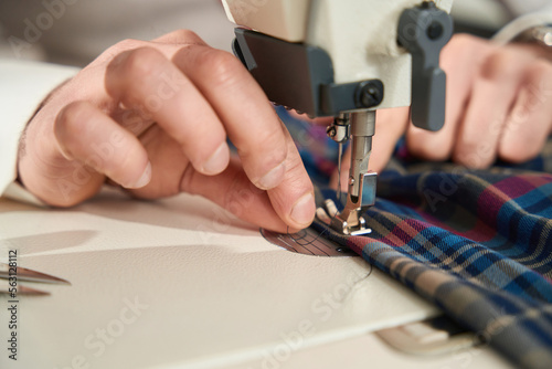 Experienced tailor is threading sewing machine before work