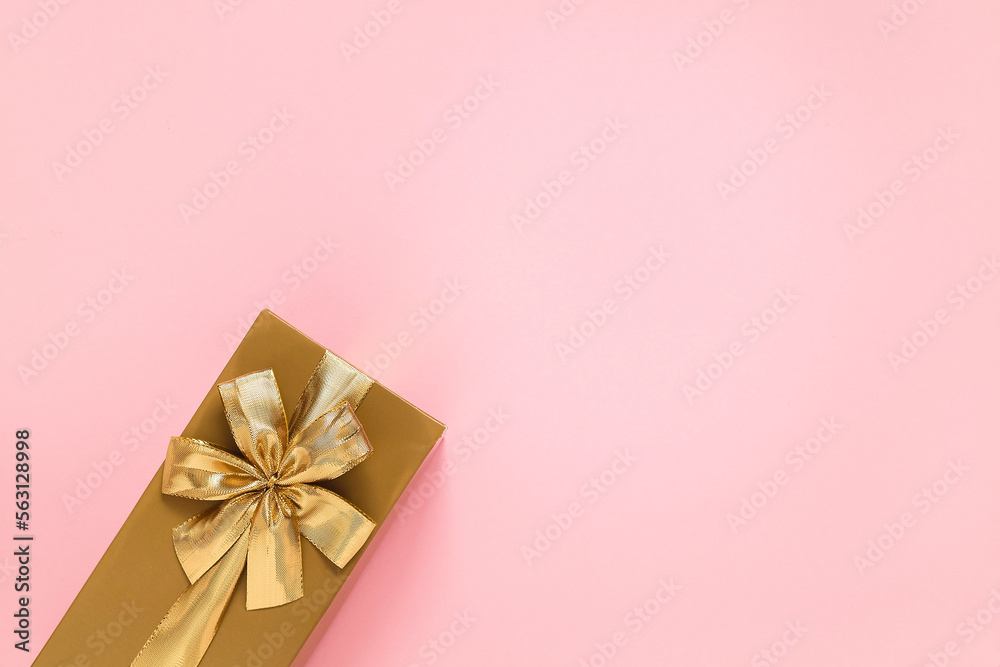 Golden gift box with golden ribbon and bow on a pink background. Top view. Copy space. Golden gift box with golden ribbon and bow on a pink background. Top view. Copy space.