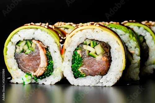 Close-up of green dragon sushi rolls with salmon, avocado, cucumber and green caviar. Dark background
