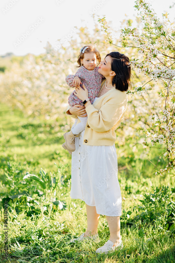 happy mother and daughter on a walk in a spring park with flowering trees. 