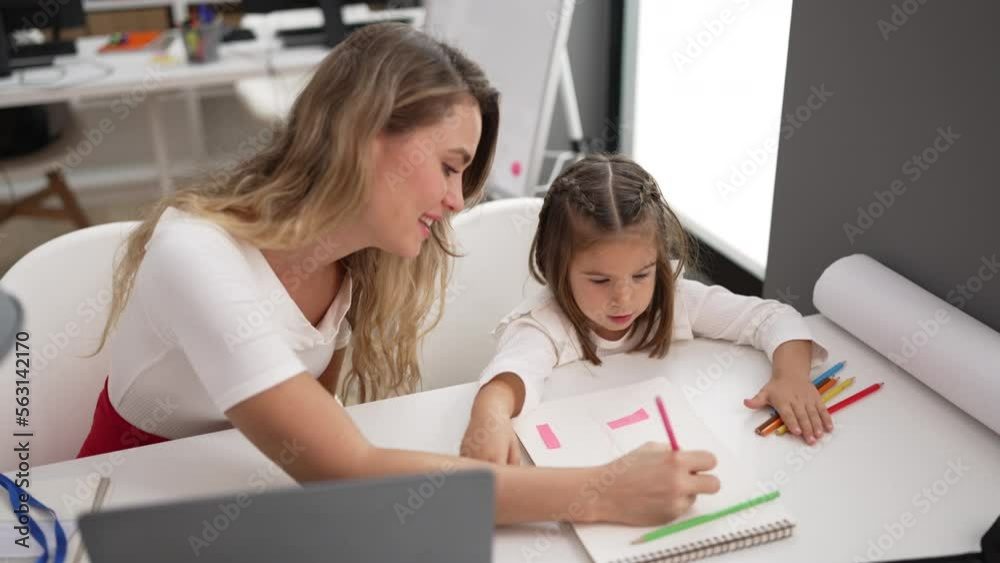 Teacher and toddler sitting on table drawing on notebook at classroom Teacher and toddler sitting on table drawing on notebook at classroom
