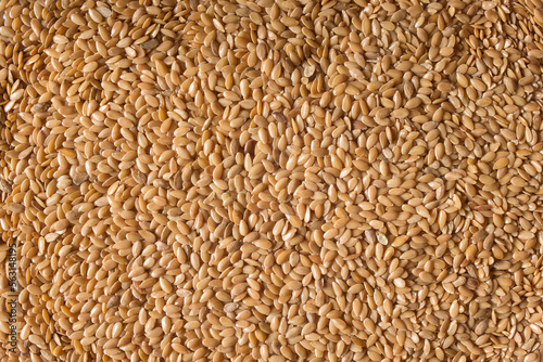 Top view of a close-up of a pile of cleaned golden flax seeds. Organic texture abstract background. Superfood.