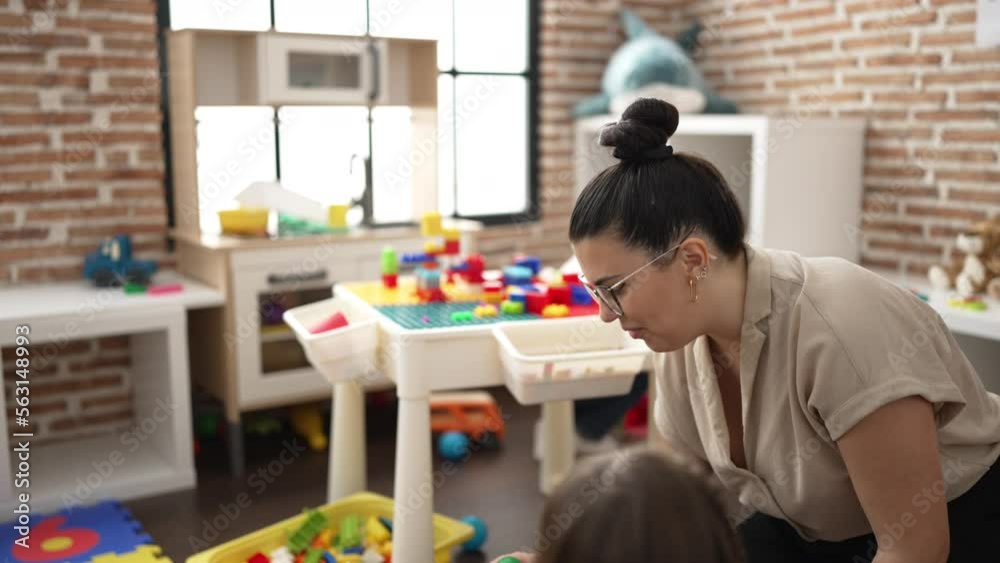 Teacher and group of kids sitting on table playing with toys at kindergarten Teacher and group of kids sitting on table playing with toys at kindergarten