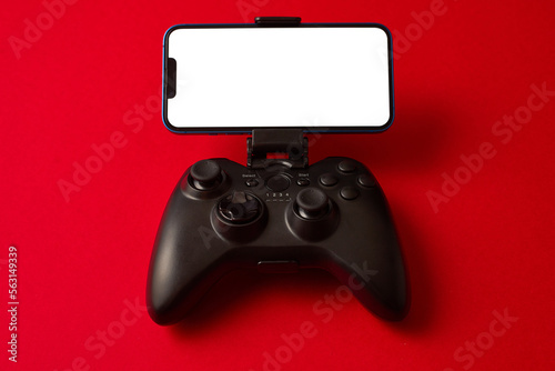 Modern black gamepad for smartphone on red background. Mobile video gaming device