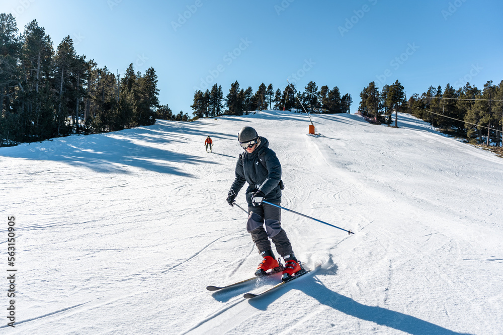 Two boys skiing down a large ski slope. - obrazy, fototapety, plakaty 